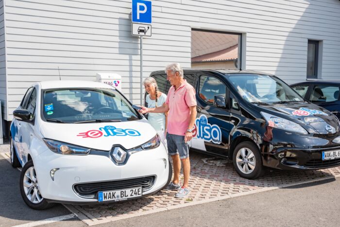 Zwei Elektrofahrzeuge Mobil mit ELISA mit Menschen und Ladestation
