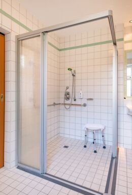 Innenaufnahme Zimmer mit barrierefreiem Badezimmer und Blick auf den Schlafbereich