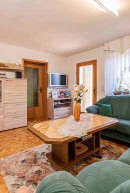 Innenaufnahme Zimmer mit Sofa, Sessel, Tisch und TV